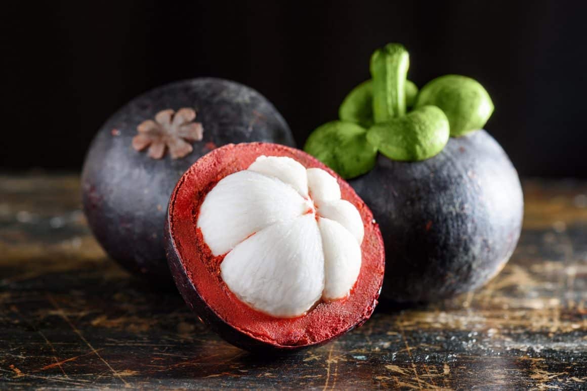 Close up cu fruct mangostan copt, asezat pe masa de lemn. Unul din fructe exotice, tropicale, dulce si gustos.