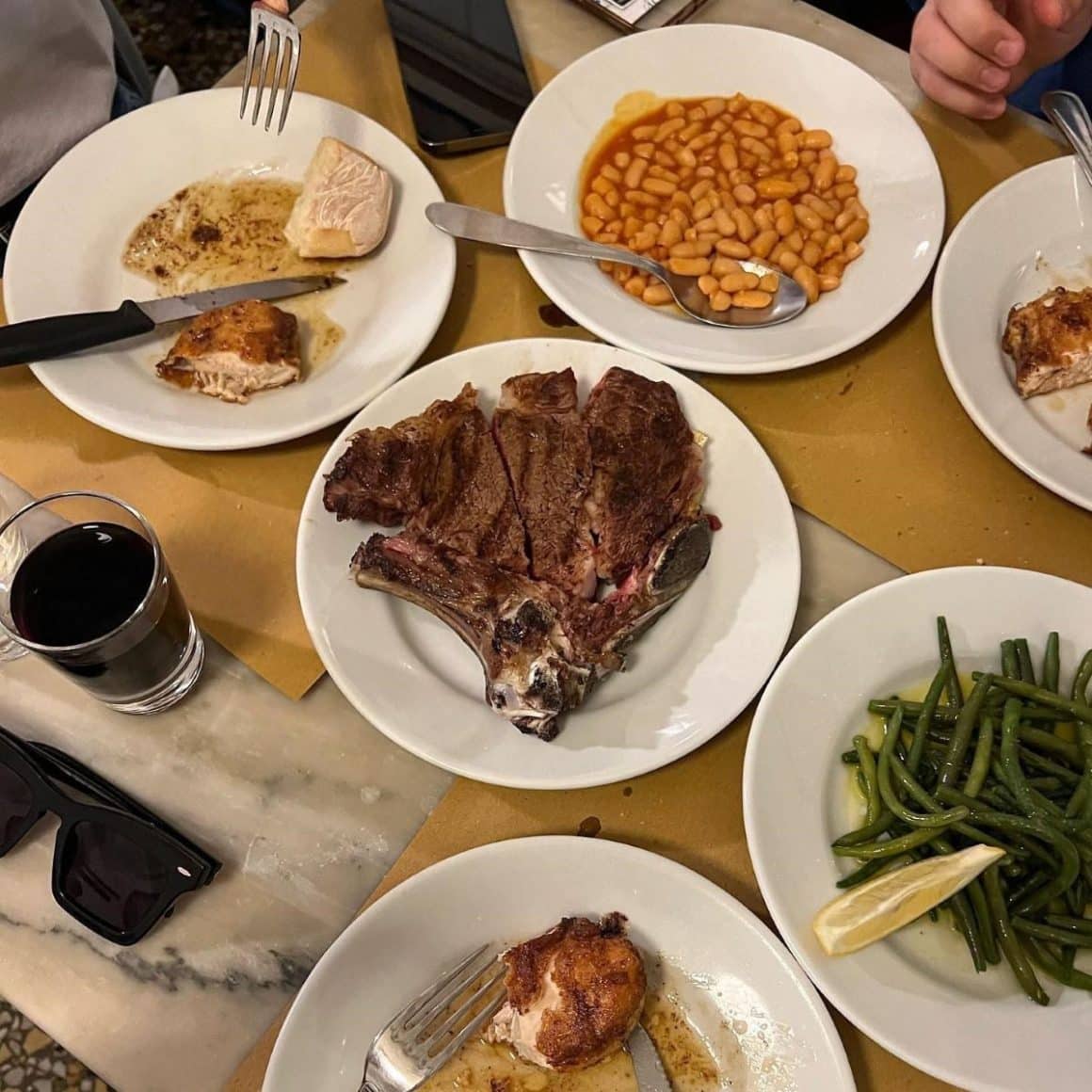 mai multe farfurii cu mancarea traditionala din toscana și cateva pahare si sticle asezate pe o masa 