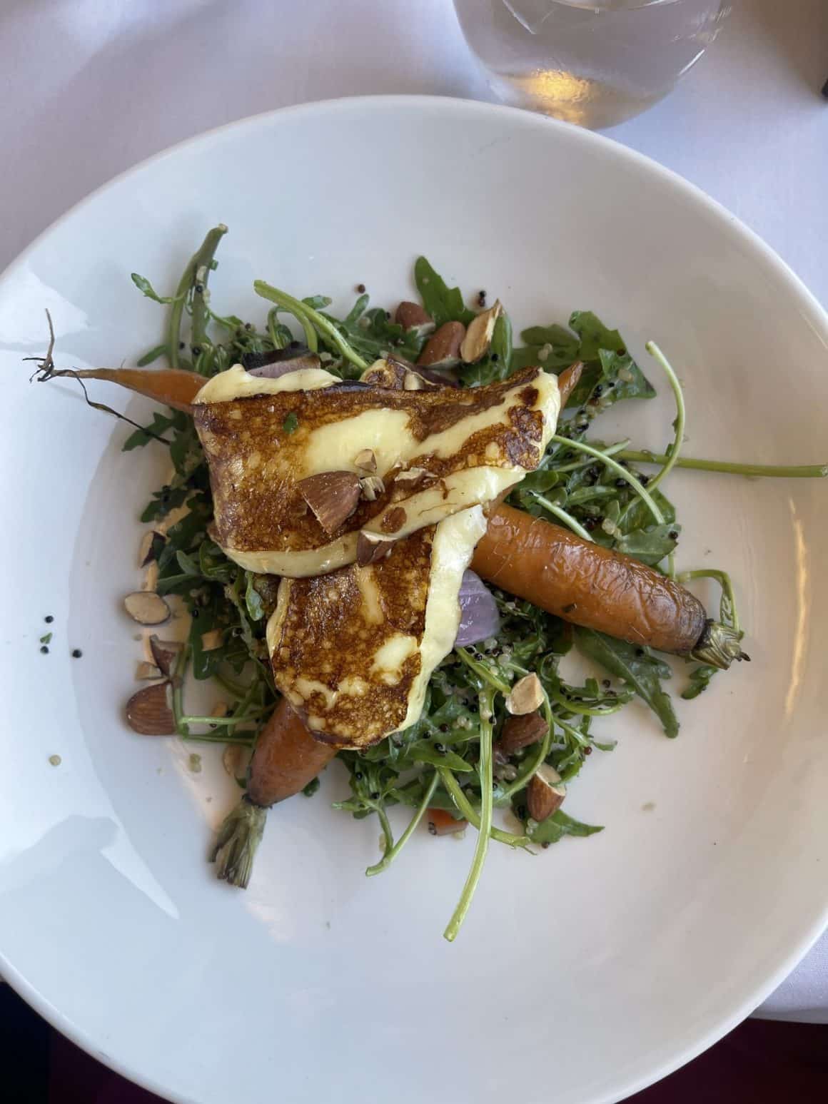 o farfurie alba de portelan cu o salata de frunze, morcovi copti și două pancakes