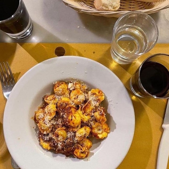 o farfurie cu mancarea traditionala din toscana și cateva pahare si sticle asezate pe o masa 