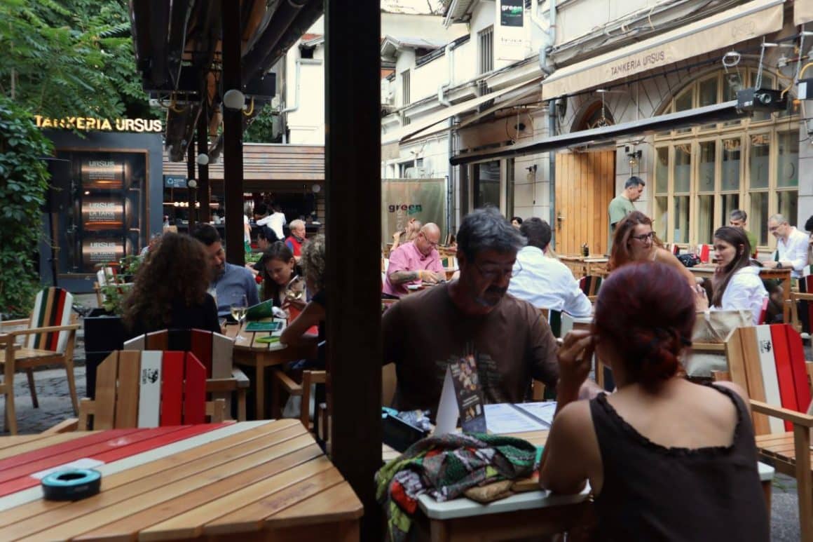 mai multi tineri stau pe scaune la una dintre mesele restaurantului green hours