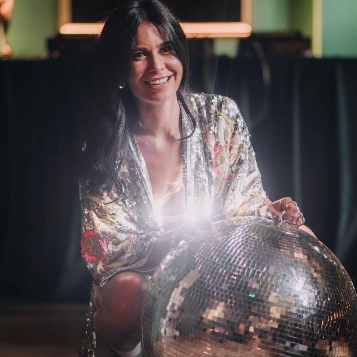 o femeie bruneta zambeste și pozeaza cu un discobol strălucitor