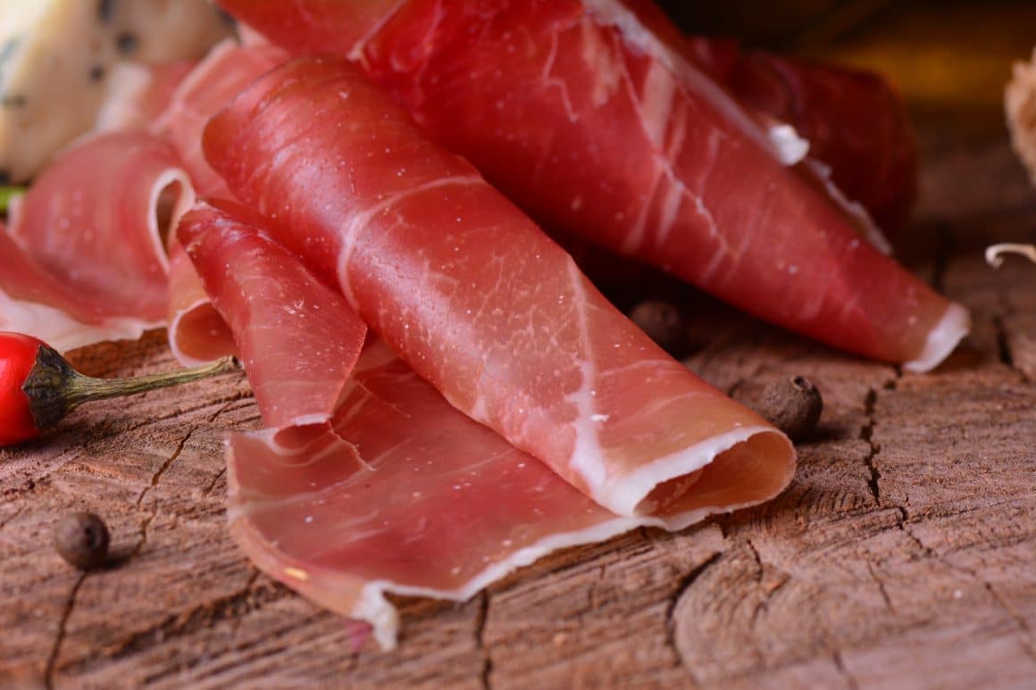 cateva felii de jamon iberico sunt rulate in forma unei tigarete si asezate pe un tocător de lemn, alaturi de cateva boabe de piper și o codita de ardei rosu. Diferența între jamon și prosciutto