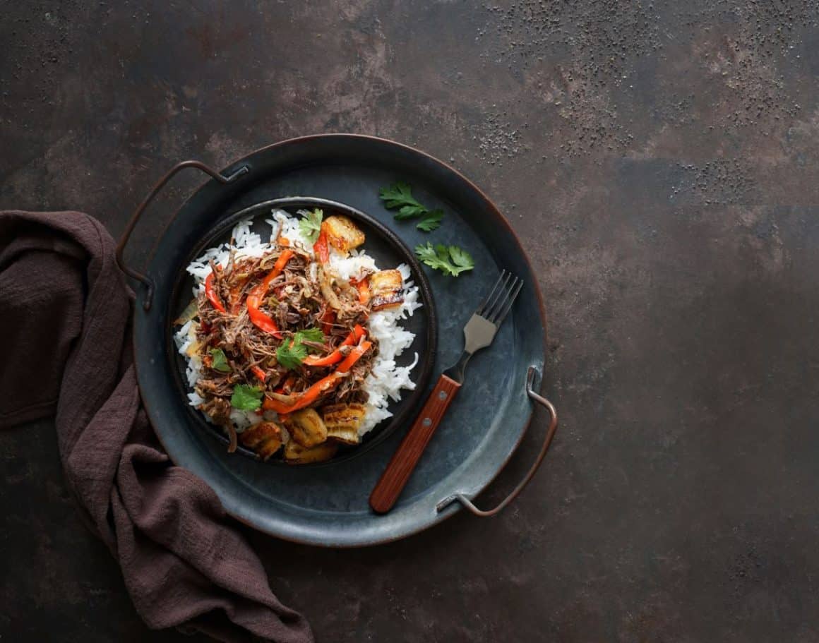 Ropa Vieja, o tocană pe bază de carne făcută cu năut, cartofi și legume este asezata pe o tava metalica cu manere, alaturi deun servet pe masa, Mâncare din tenerife