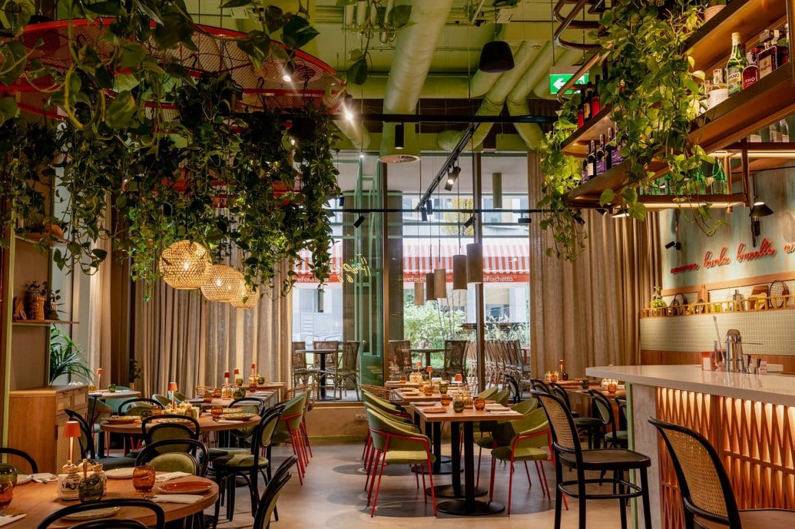 imagine de ansamblu din restaurant Ave Forchetta, cu mobilier in nuante de oliv si oranj, cu multe plante decorative. Unde să mergei la prima întâlnire