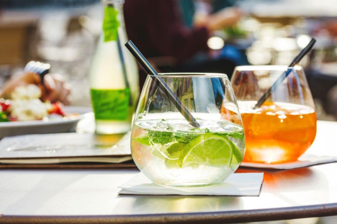 doua pahare cu bauturi alcoolice și fructe sunt asezate pe o masă dintr-un aperitivo bar