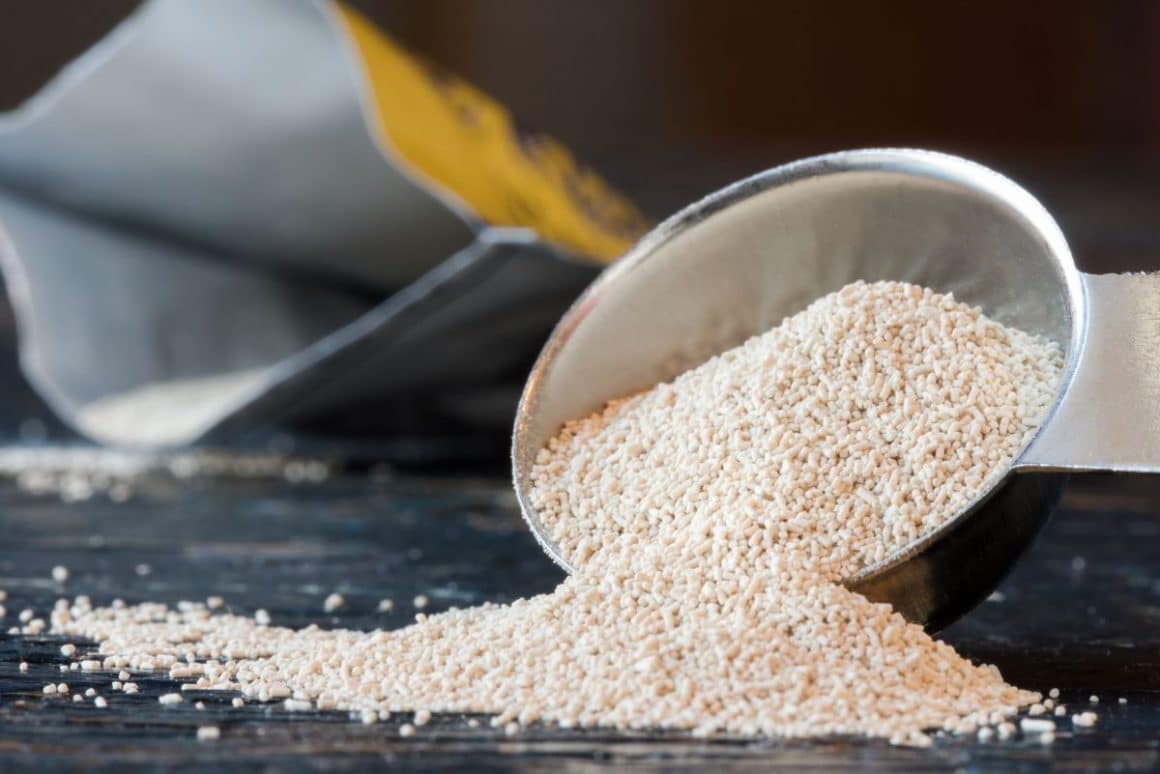 un pachet de drojdie salbatica este deschis, iar in fata lui este o masura de bucatarie plina cu granule de drojdie inactivă