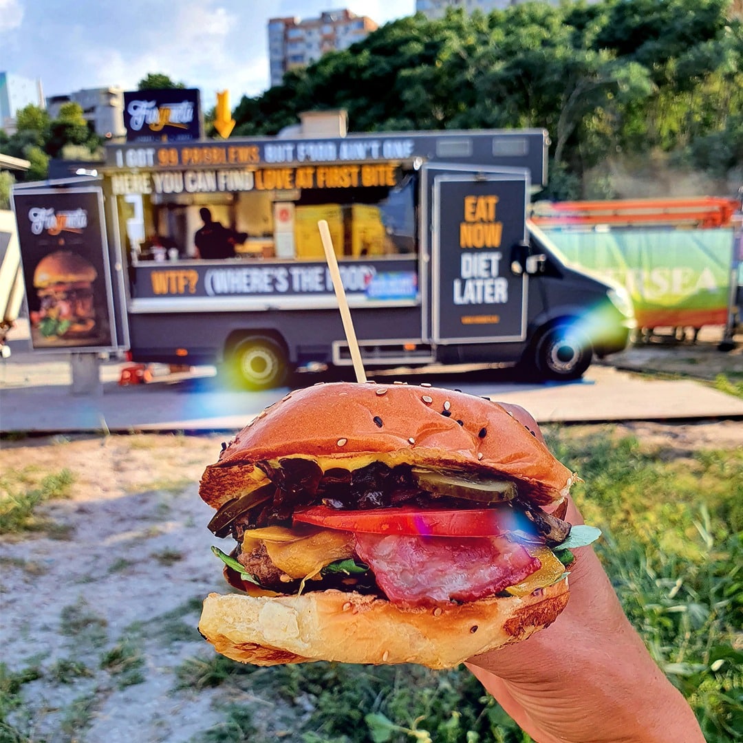 camioneta de foodtruck de la Furgoneta si in prim plan un burger. Street food în Bucureti