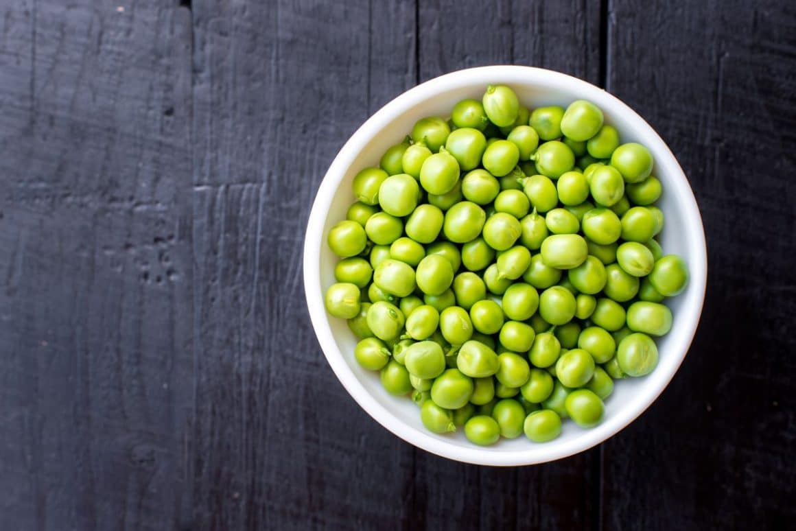 un bol alb este plin cu boabe de maare, fotografiat pe o masa de lemn negru