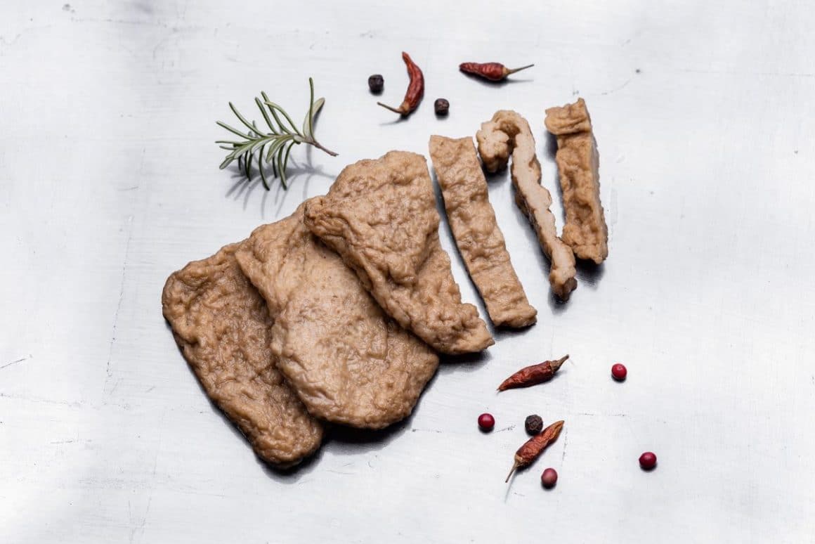 o felie de seitan, o sursă populară de proteine vegetale, este taiata în bucăți și ornata cu ardei chili, rozmarin și piper rosu