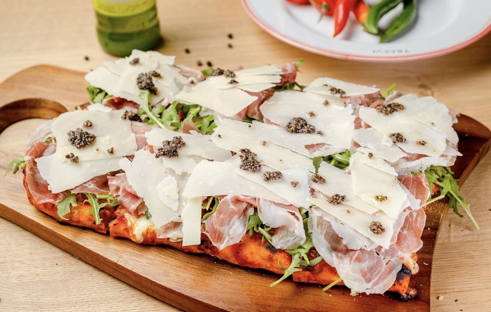 felie mare de pizza servita pe blat de lemn laTreevi Pizza & Gin Bar