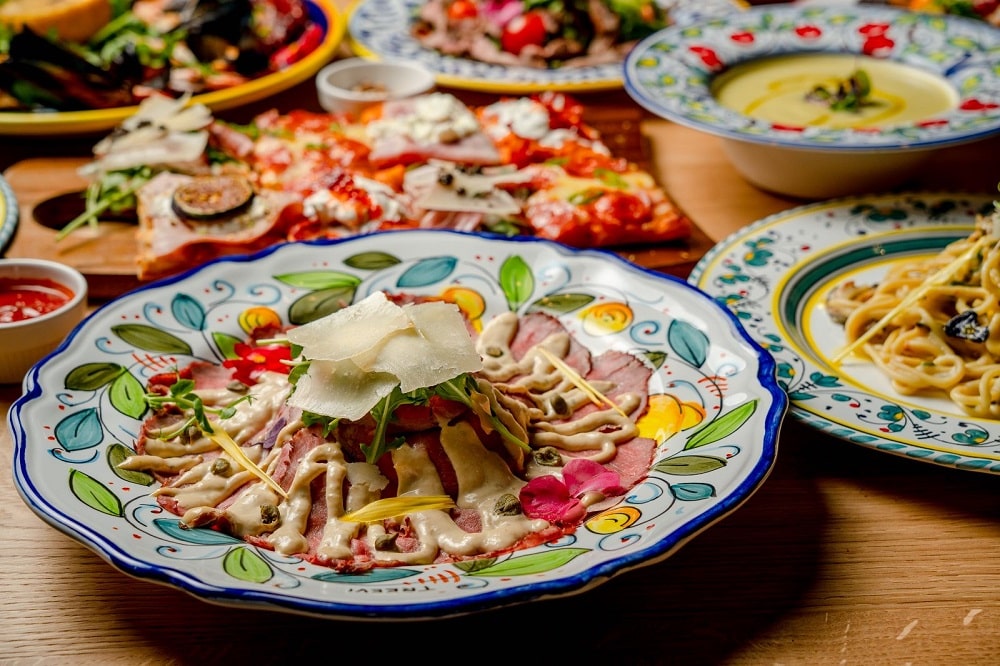 mai multe ferfurii pictate rustic, in stil mediteranean, cu diverse preparate specifice bucatariei italiene