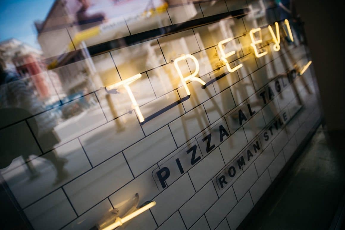 Prim plan cu vitrina de la Treevi Pizza Al Taglio, cu litere volumetrice luminoase.