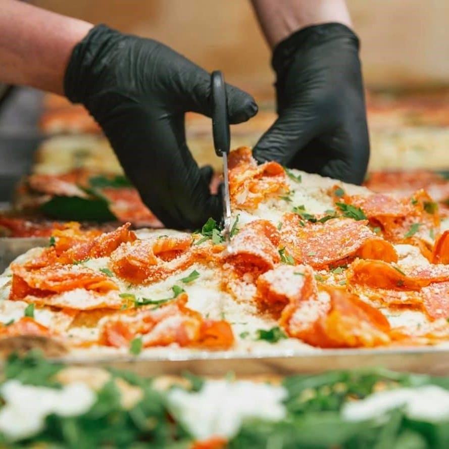 cineva taie cu foarfeca felii de pizza