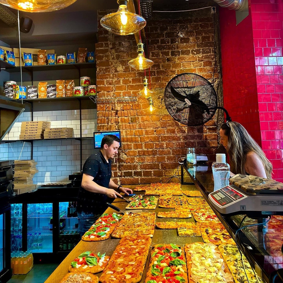 Vanzator serveste o femeie cu o felie de pizza