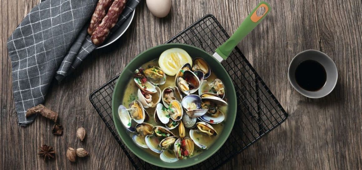 o portiede scoici sunt asezate intr-o tigaie verde, deasupra unui gratar de metal