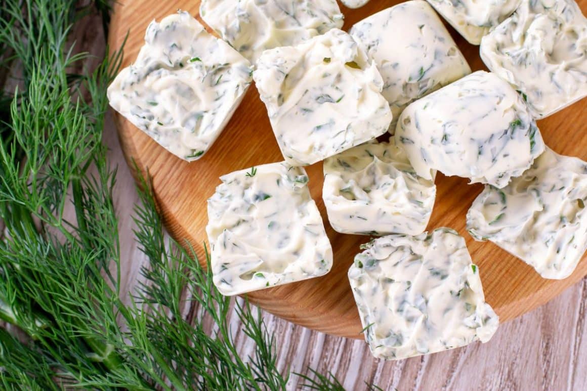 mai multe cubulete de unt aromatizat cu verdeturi sunt asezate pe un tocator de lemn, alaturi de cateva fire de marar. Metode de a păstra ierburile aromatice