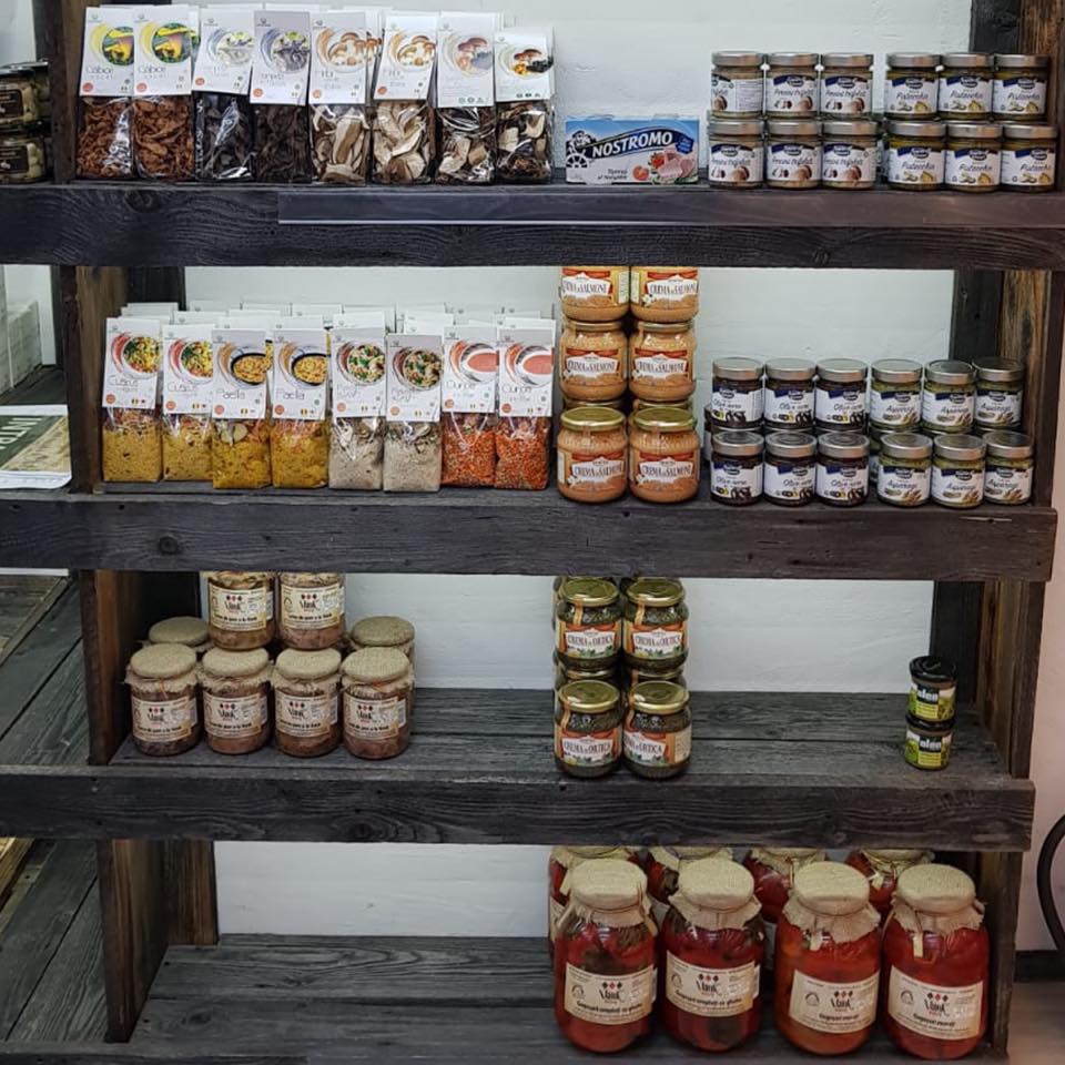 rafturi de magazin, din lemn, pe care sunt asezate mai multe borcane de zacusca de la producătorii locali