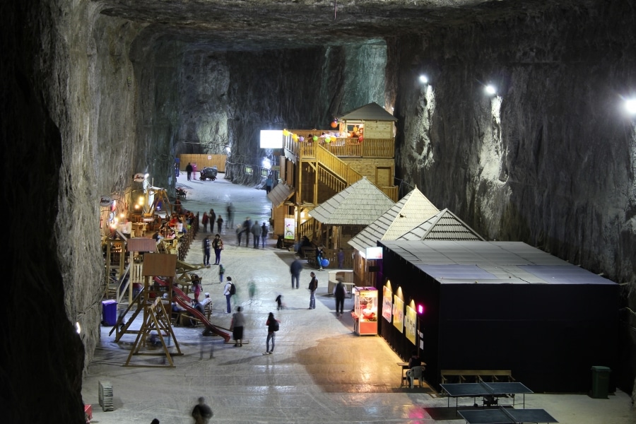 interiorul salinei praid, cu câteva construcții de lemn și vizitatori printre ele