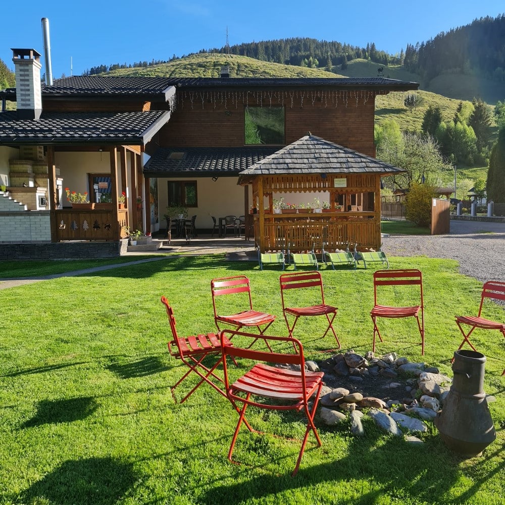 scaune in jurul unei vatre de foc de tabara iar in fundal o cabanuta la Camping De Vuurplaats