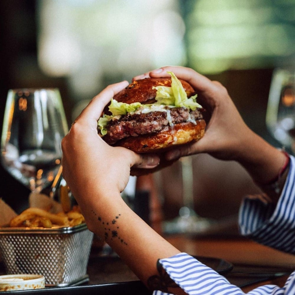 persoana tina in mana un burger de vita