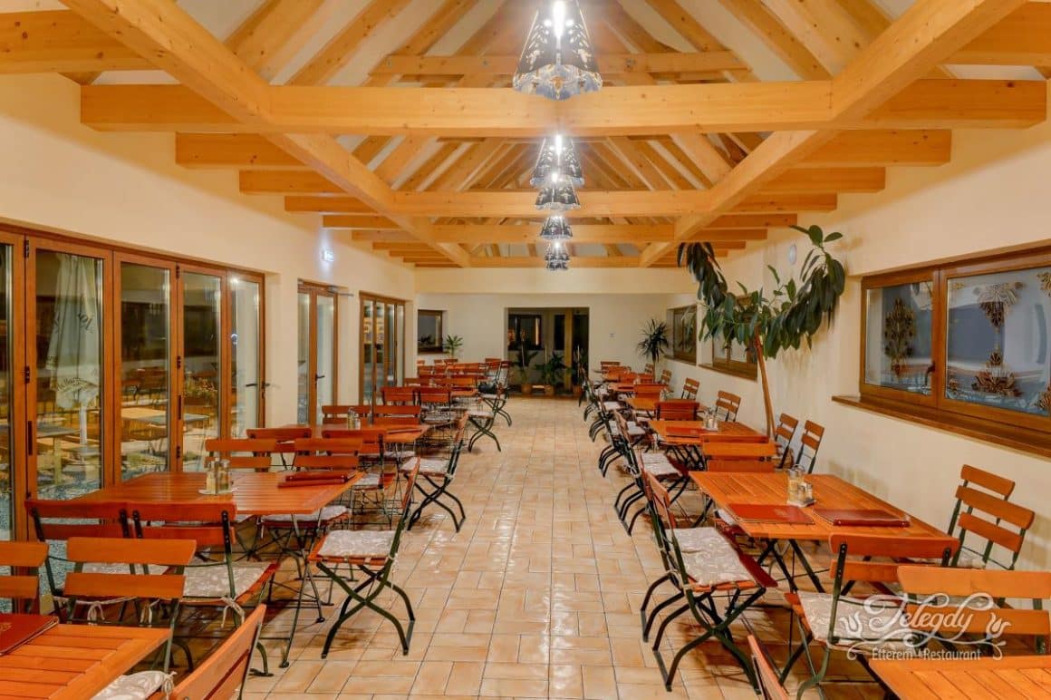 sala de mese a unui restaurant rustic, cu mese scaune și grinzi de lemn și peretii albi