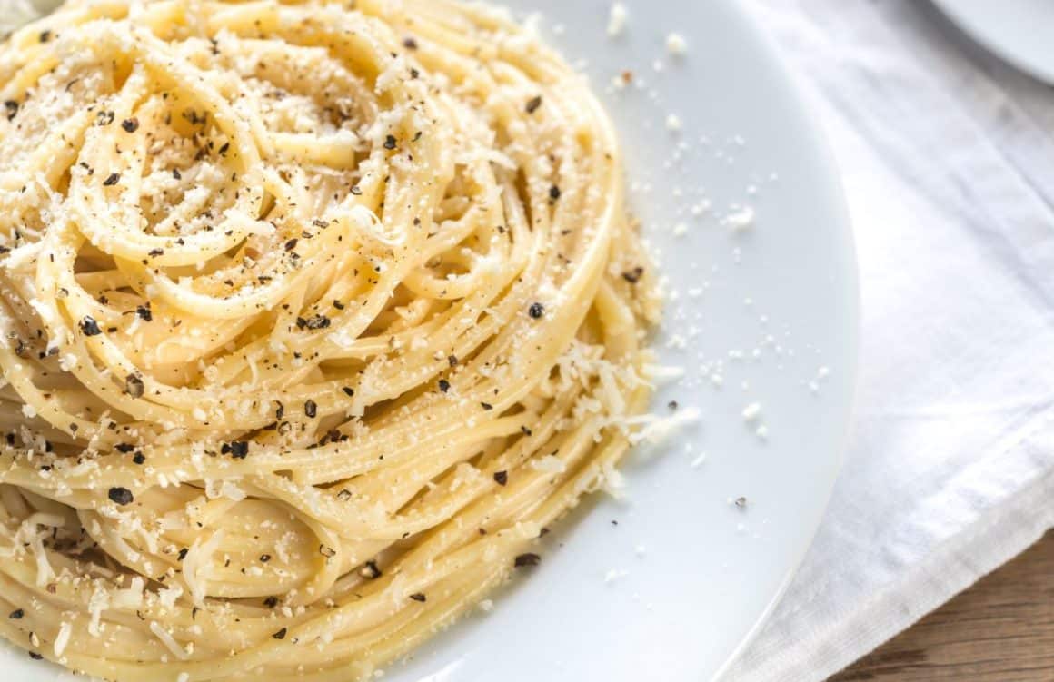 o prtie de paste cacio e pepe, asezate in spirală, pe o farfurie alba