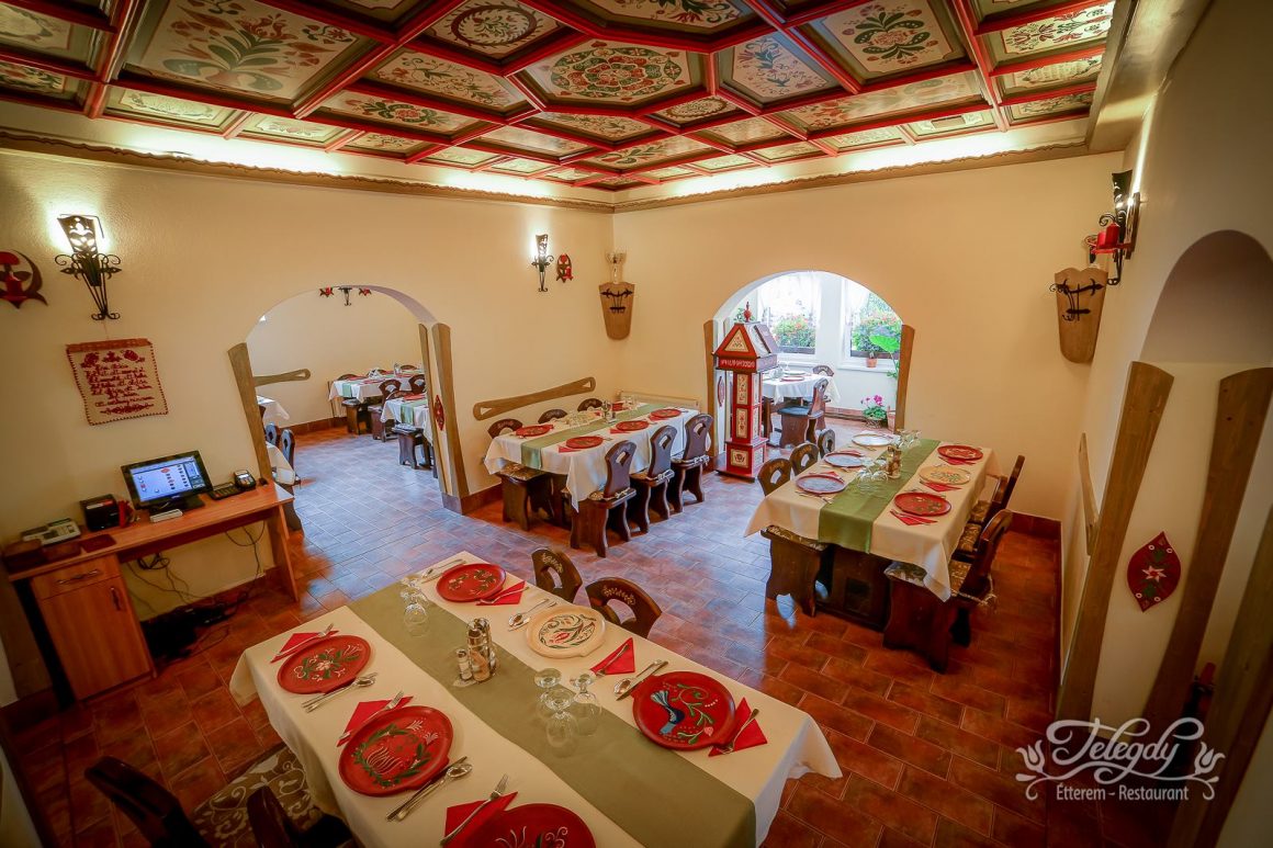 sala de mese a unui restaurant rustic, cu mese acoperite cu fețe de masă și farfurii, cu tavan decorat puternic și arcade semirotunde