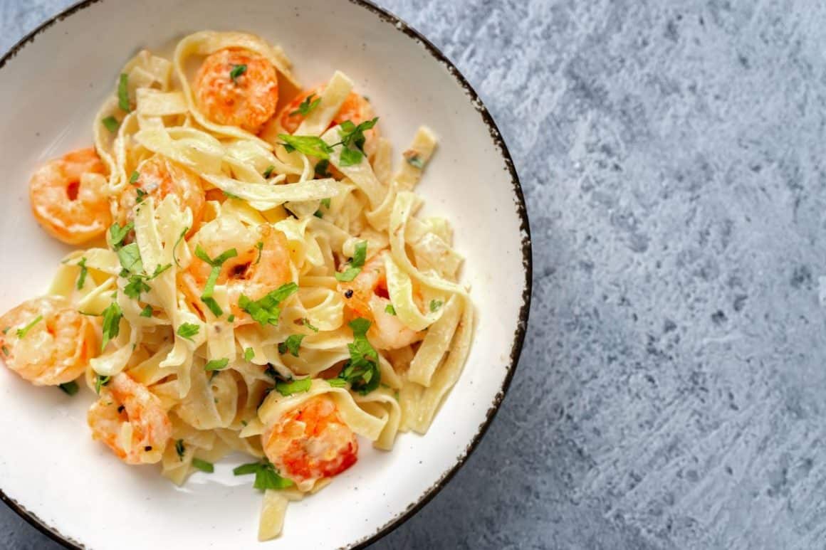 o portie de paste tagliatele cu sos Alfredo, servită pe o farfurie albă, cu margini negre. Unul din cele mai populare sosuri italiene pentru paste