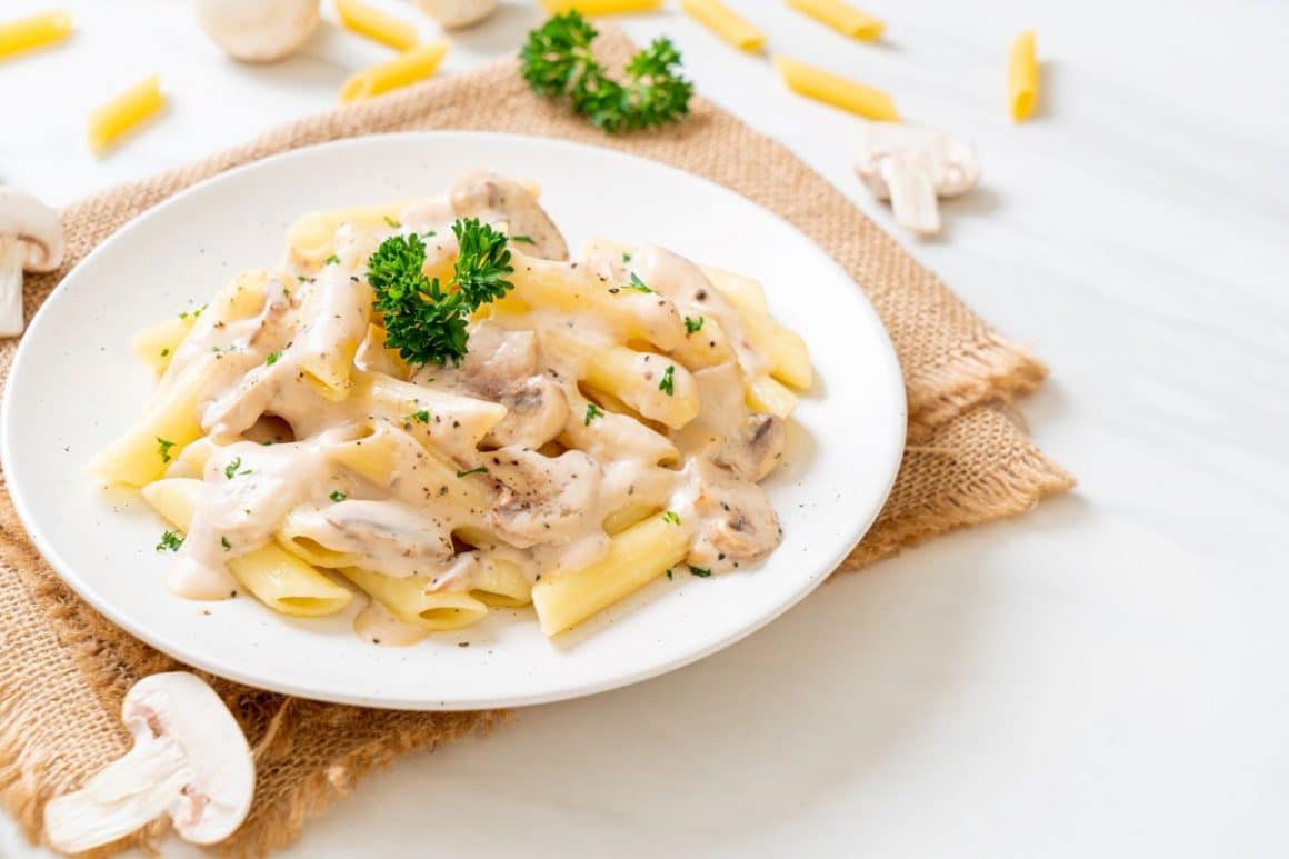o portie de paste cu sos carbonara servită într-o farfurie alba, asezată pe un ștergar