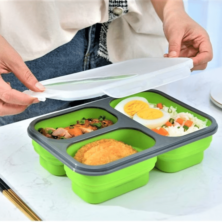 close up cu o persoană care așază mai multe tipuri de mâncare într-o caserola din silicon. Cutii de prânz 