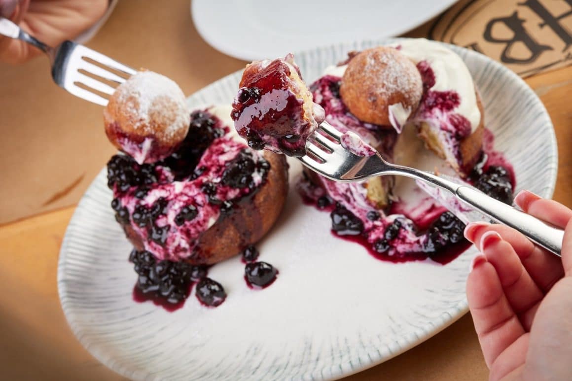 cineva mananca dintr-o farfurie cu papanasi de la Hanu Berarilor, unde mâncăm papanași buni în București