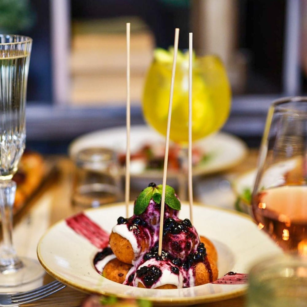 farfurie cu papanasi micuti, in care sunt infipte bete de frigarui pentru servire