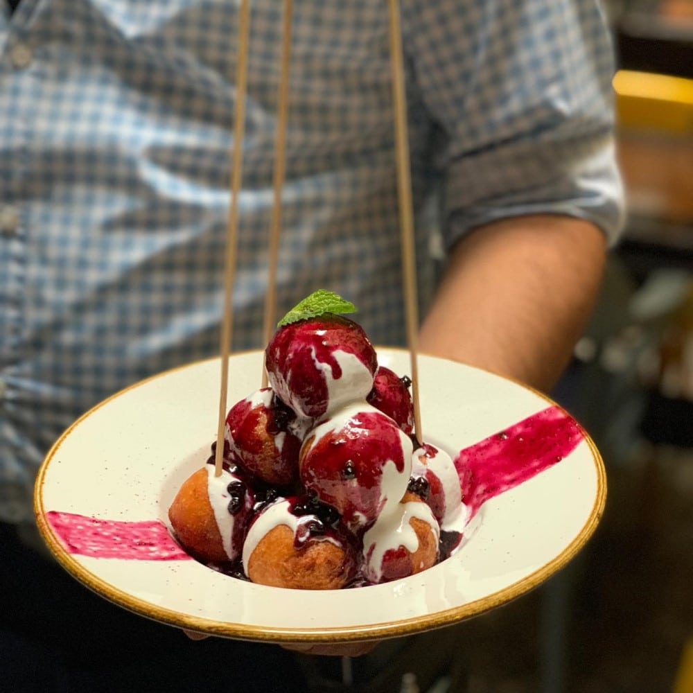 close up cu o farfurie plina cu bilute de papanasi cu smantana si dulceata de la Stadio, unde mâncăm papanași buni în București