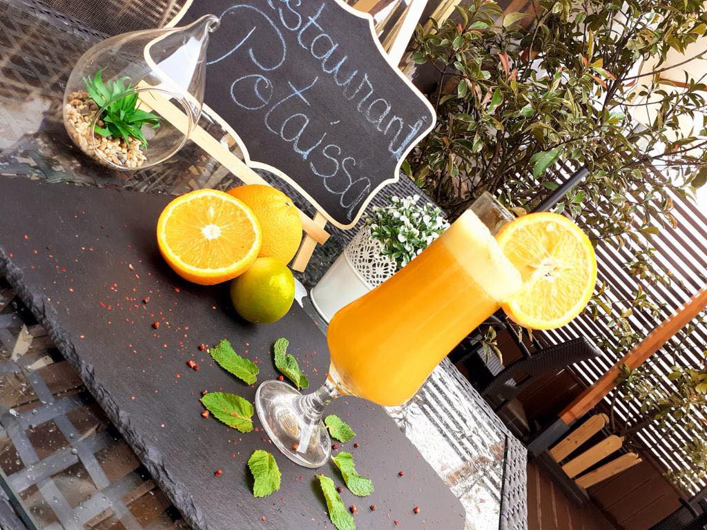 un cocktail este așezat pe masă, alături de câteva citrice și un terrariu de sticlă.