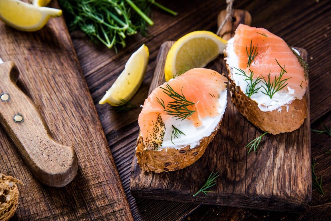 Variante de sandvișuri: somon cu brânză cottage si toast, fotografiate pe un tocator de lemn