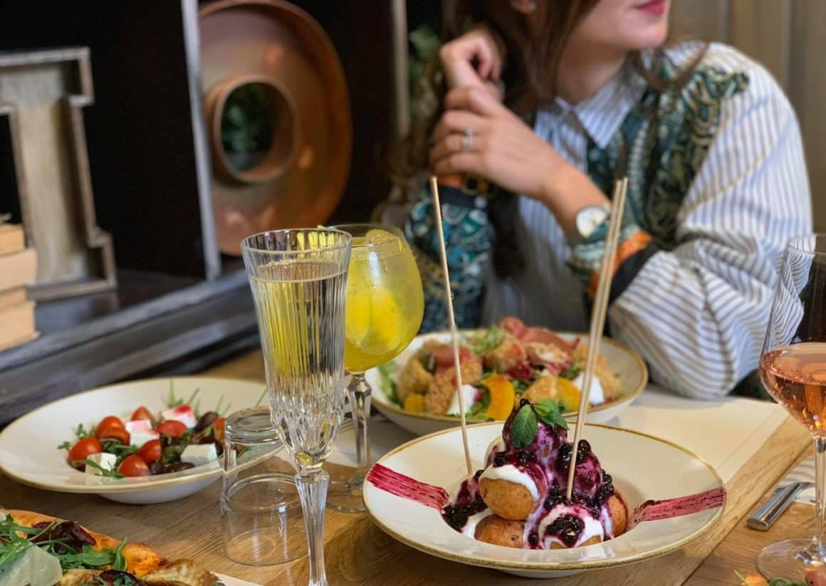 masa plina cu mancare: salata, fel principal si in prim plan o farfurie cu panași buni din București la restaurantele Stadio