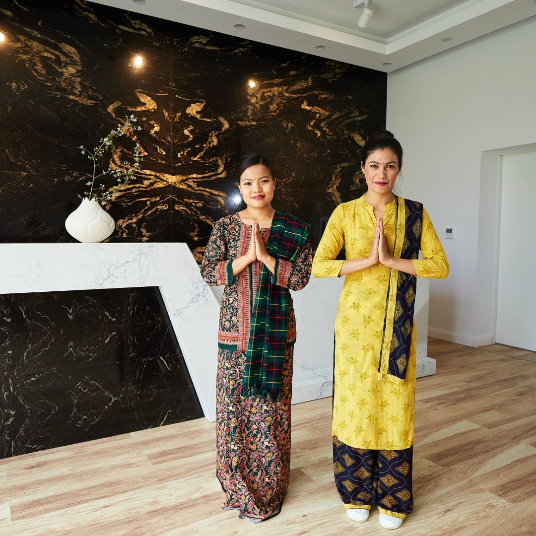 două femei asiatice intâmpină cu un gest făcut cu mâinile invitații intr-un spa din românia