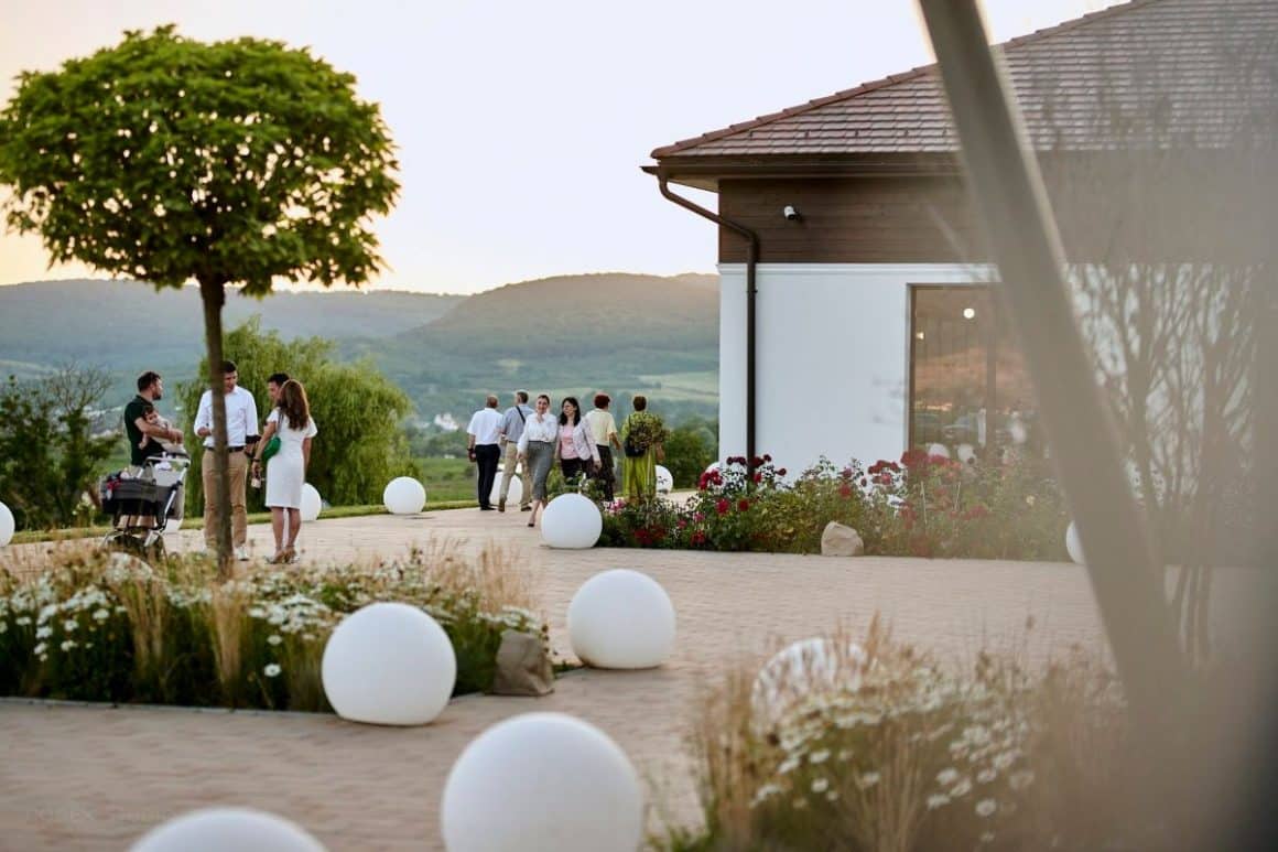 oameni stau de vorbă în curtea Cramei Jelna din Bistrița Năsăud