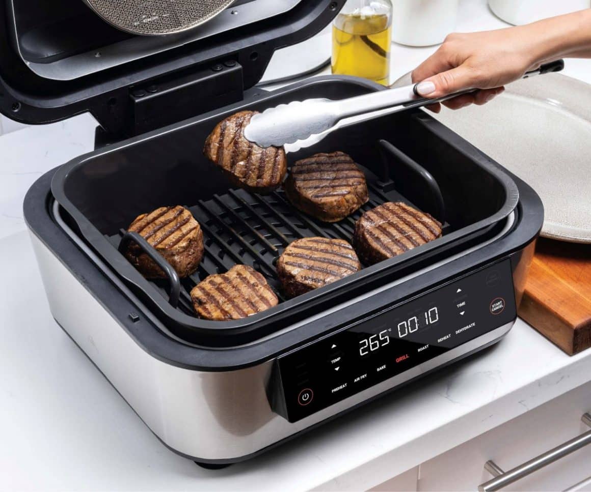 o mana de femeie intoarce o chiftea de burger intr-un gadget de bucatarie modern