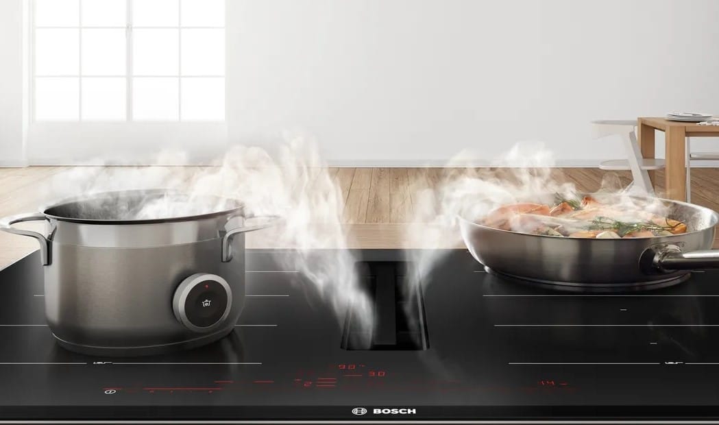 o oala si o tigaie asezate pe o plita cu inductie cu hota incorporata, de la Bosch. gadgeturi de bucătărie