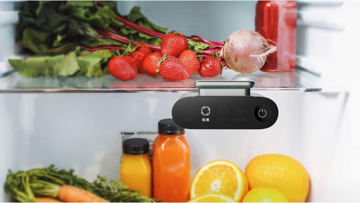 un dezodorizant de frigider este plasat pe marginea unui raft de frigider, pe care sunt asezate mai multe legume