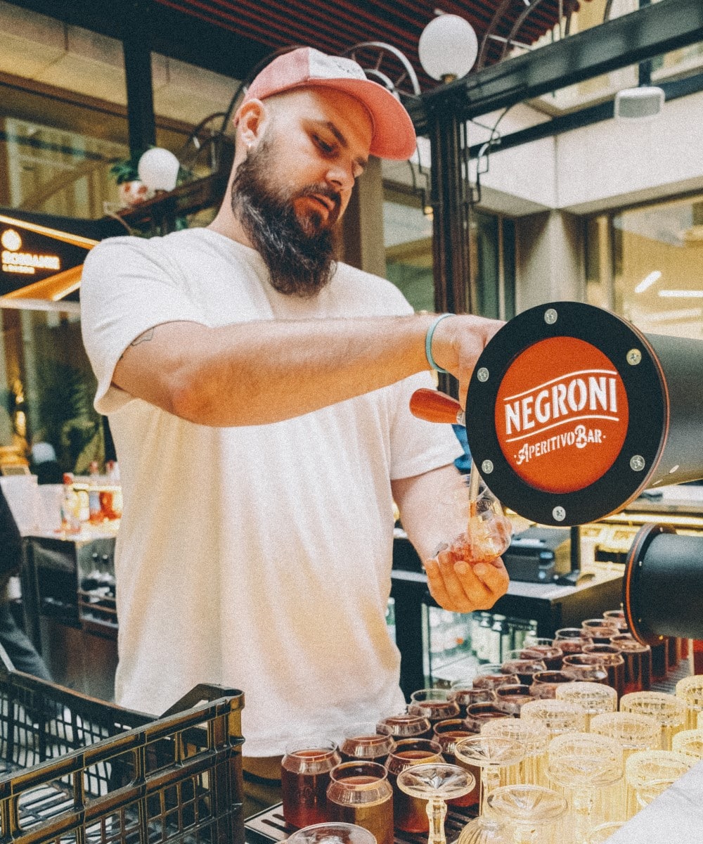barman toarna intr-un pahar Negroni la tap