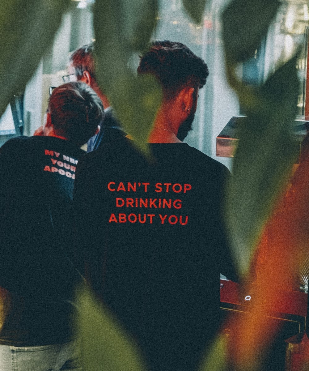 barbat fotografiat din spate cu tricou negru cu mesaj Cant stop drinking about you
