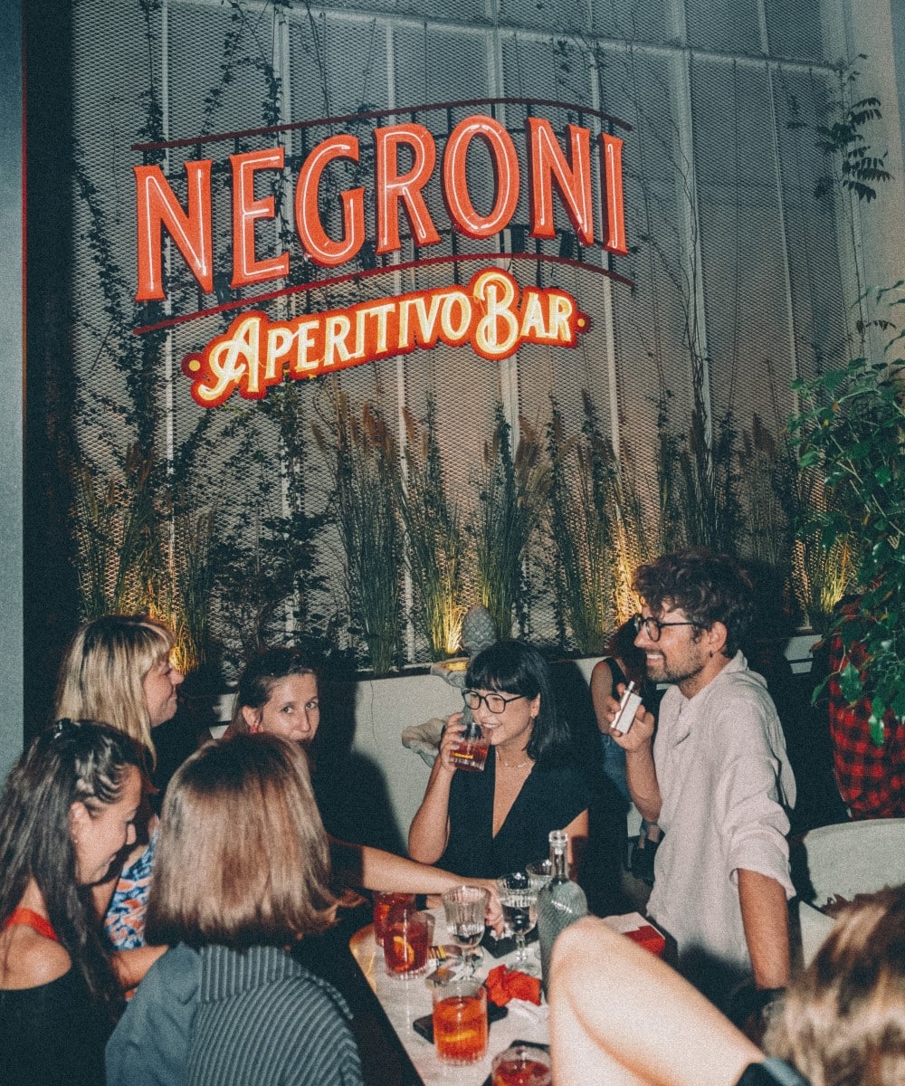oaspeti stau de vorba si se se simt bine la un pahar de cockatil Negroni