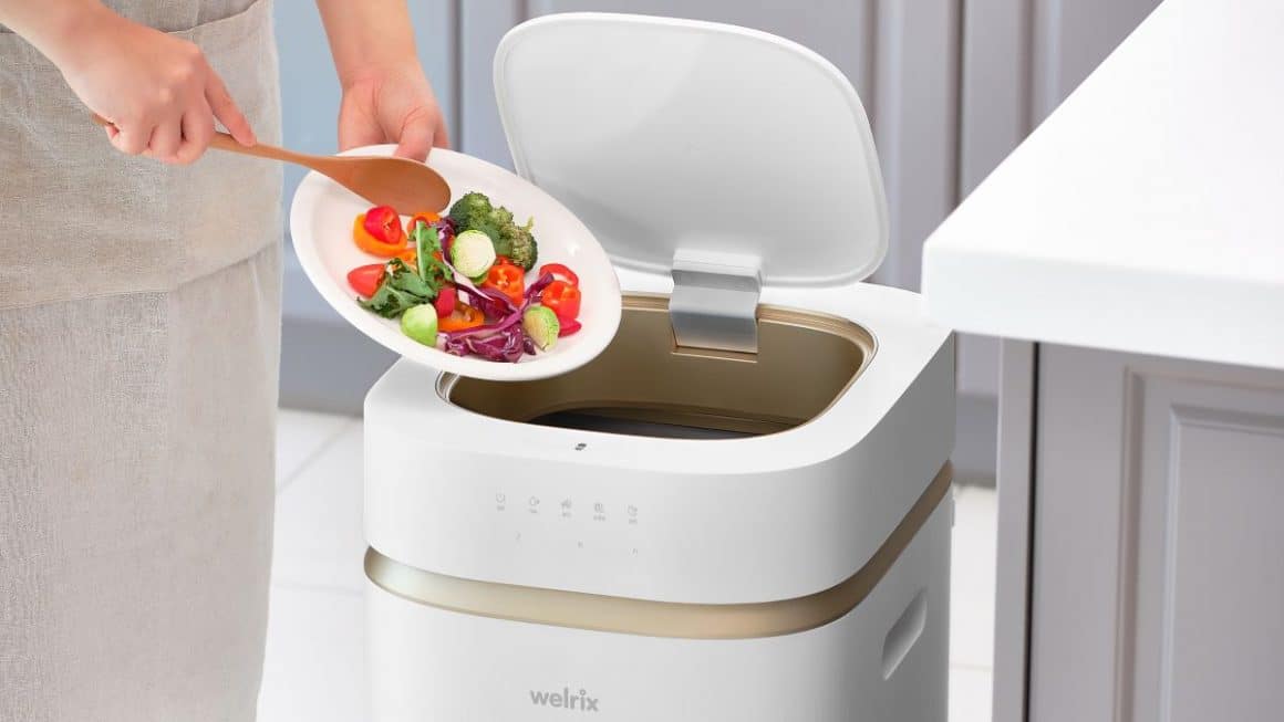 o femeie arunca la gunoi mia multe legume de pe o farfurie, intr-un cos de gunoi inteligent, unul dintre cele mai noi gadgetri de bucatarie