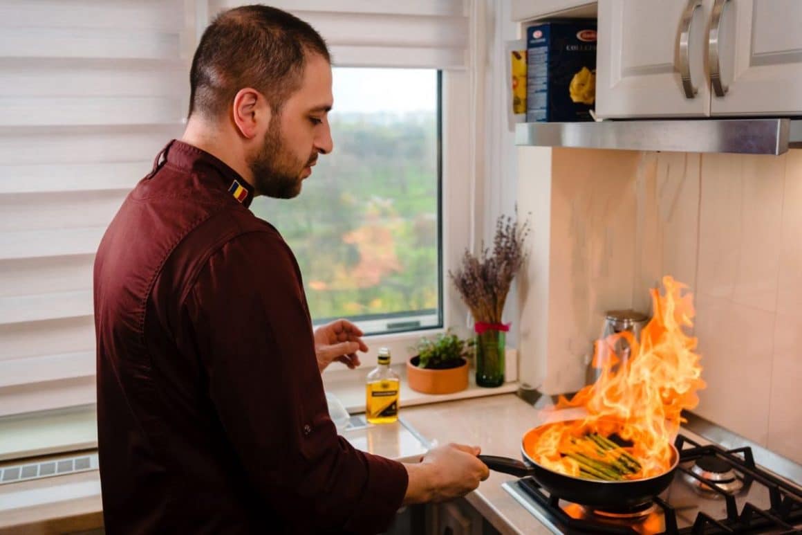 un bucătar personal flambează o porție de sparanghel într-o bucătărie de casă