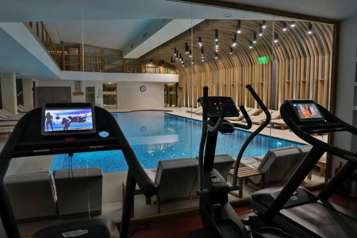 mai multe paarate de fitness sunt asezate in fata unei piscine interioare