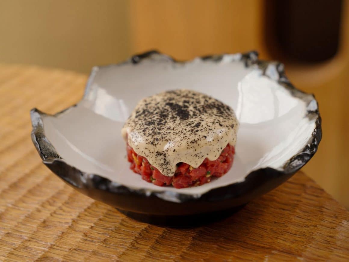 o portie de steak tartar, un fel traditional de mâncat în Bruges, într-o farfurie modernă, cu un sos alb și mult piper negru