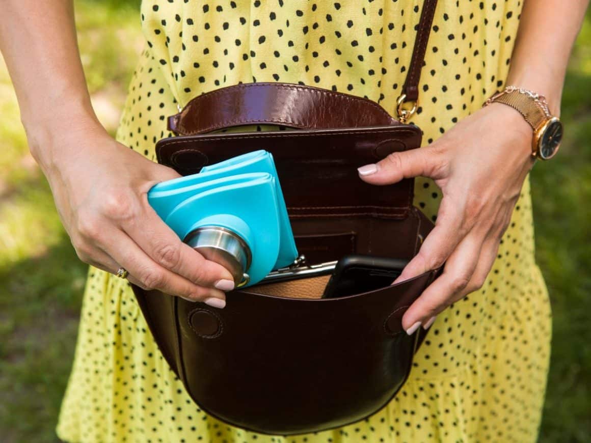 o femeie in rochie galbena aseaza in poseta ei o sticla de apa origami pliata